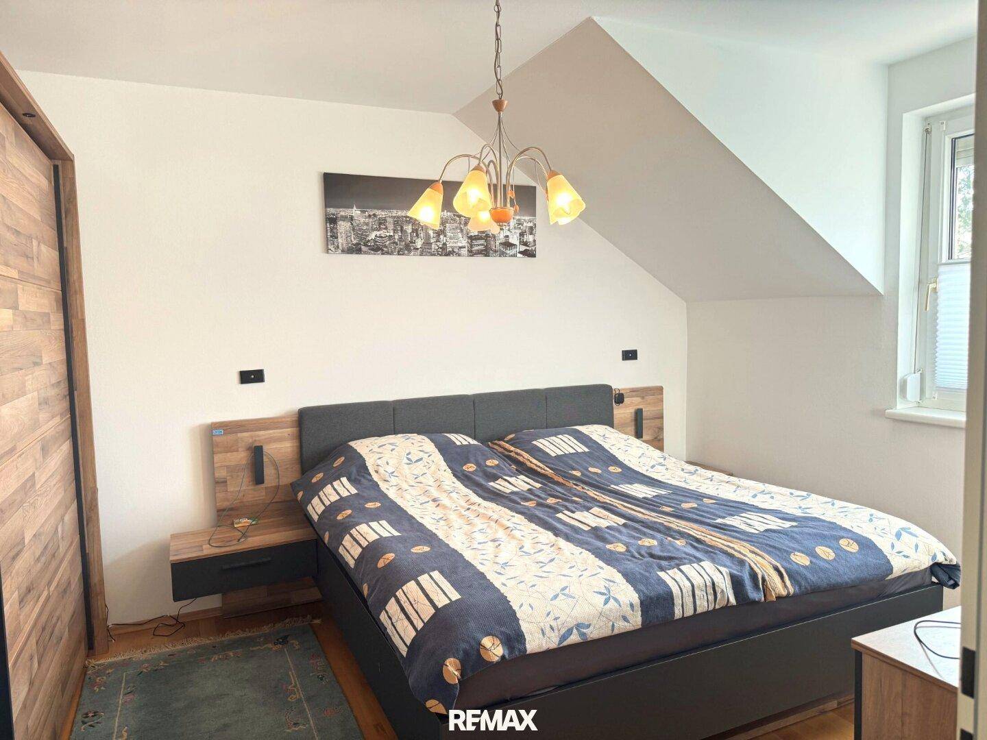 Schlafzimmer im Dachgeschoss mit Doppelbett, Holzelementen und schräger Decke.