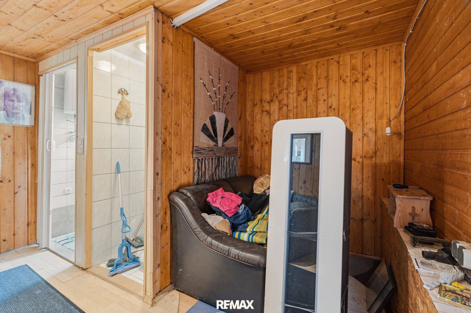 Schmaler Flur mit Holzvertäfelung und Blick auf das geflieste Badezimmer mit Schiebetür.