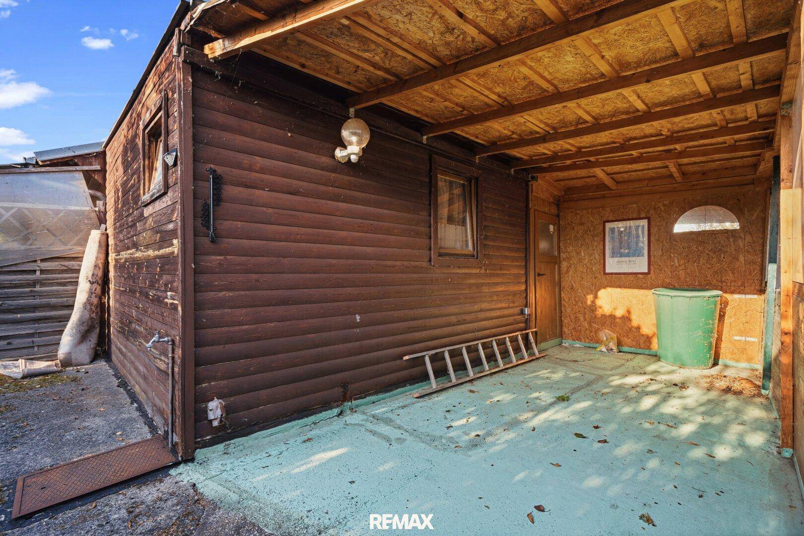 Überdachter Außenbereich neben dem Holzhaus, ideal als Carport oder Lagerfläche.