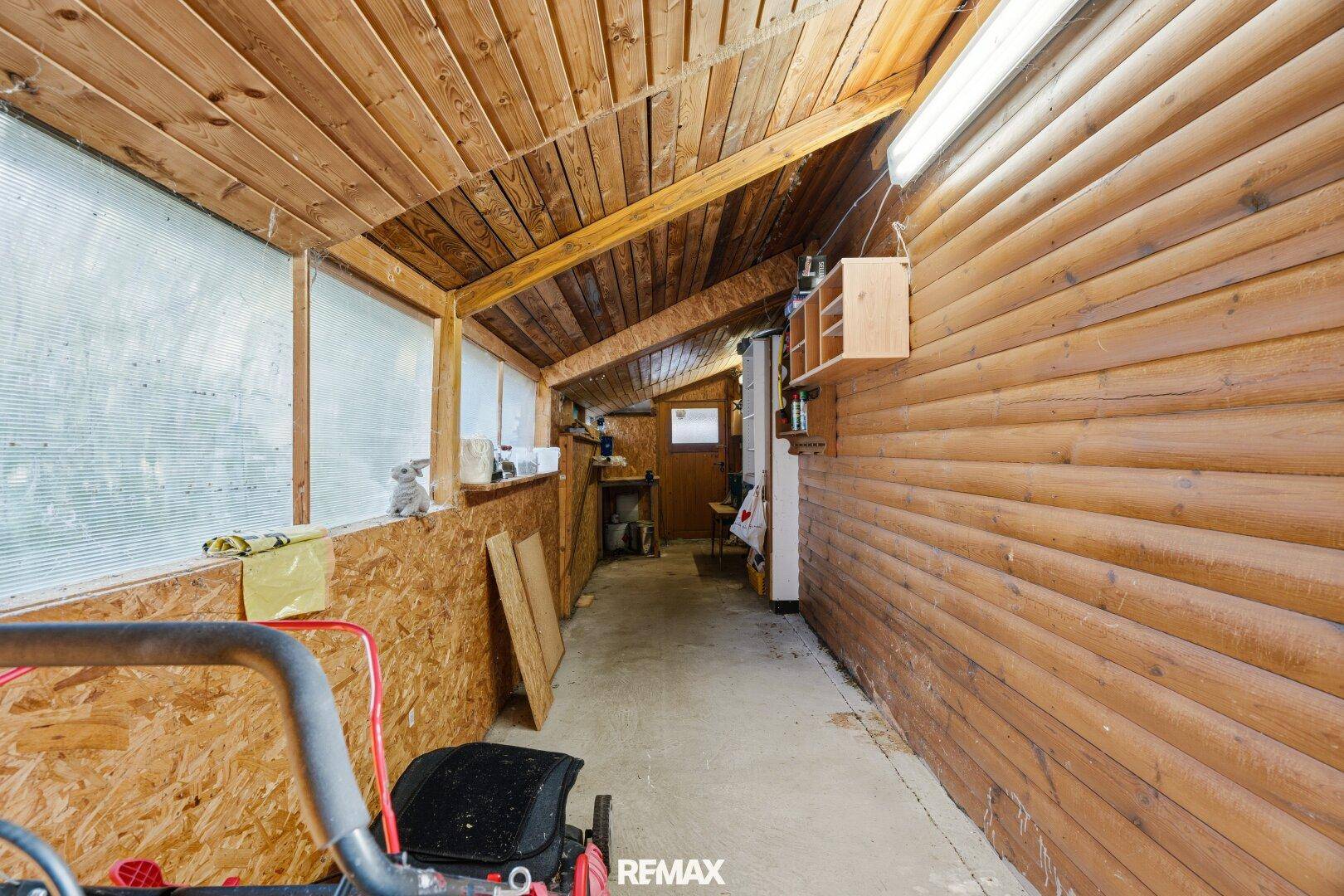 Langer Abstellraum mit Holzverkleidung, Regalen und Blick auf den Außenbereich.