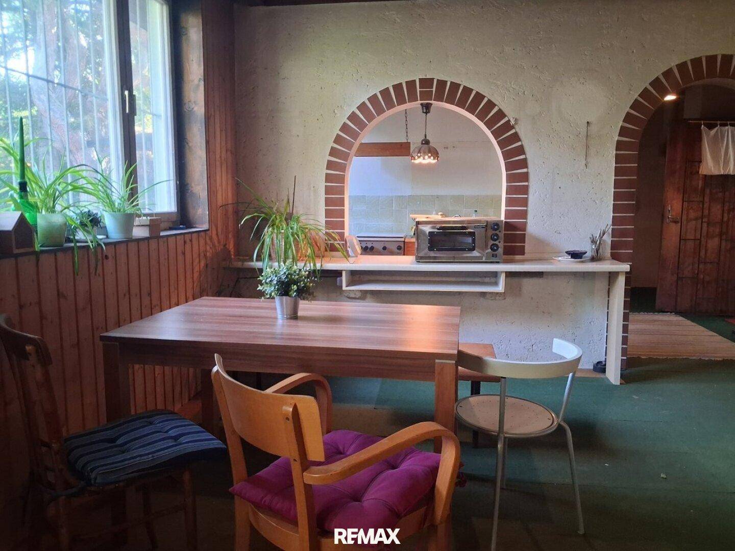 Gemütlicher Essbereich mit Holztisch, Stühlen und einem Durchgang zur Küche mit Bogen.