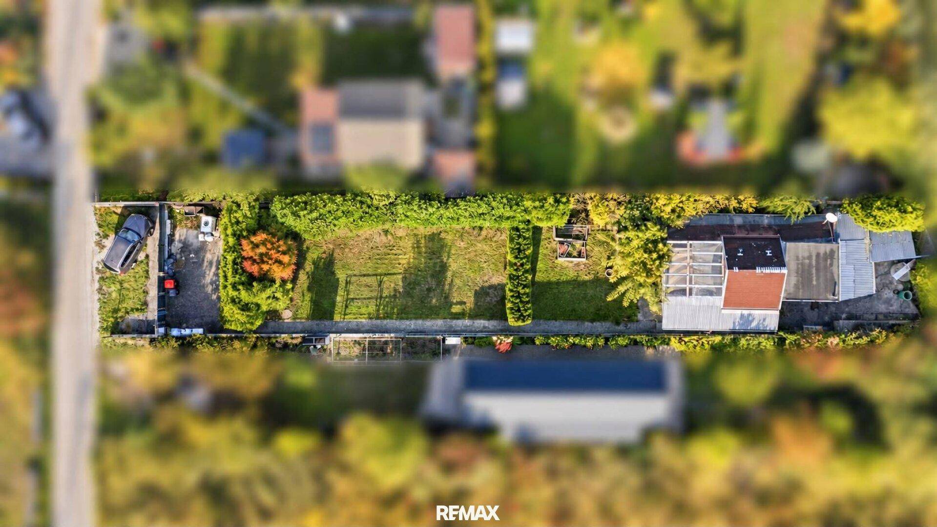 Luftaufnahme eines langgestreckten Grundstücks mit Wohnhaus, Gartenbereich und Zufahrt.