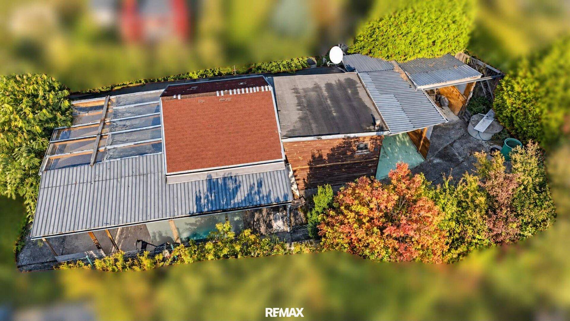 Detailansicht des Wohnhauses von oben mit verschiedenen Dachformen und umgebender Vegetation.