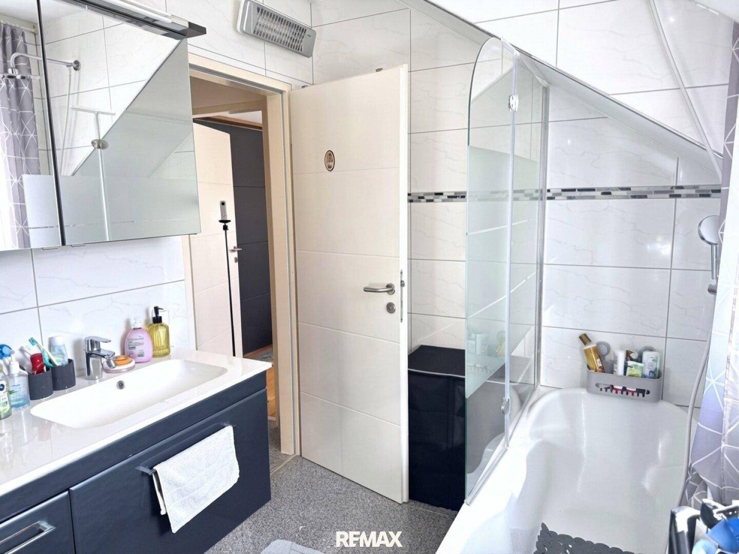 Modern gefliestes Badezimmer mit Badewanne, Duschabtrennung und Einzelwaschbecken.