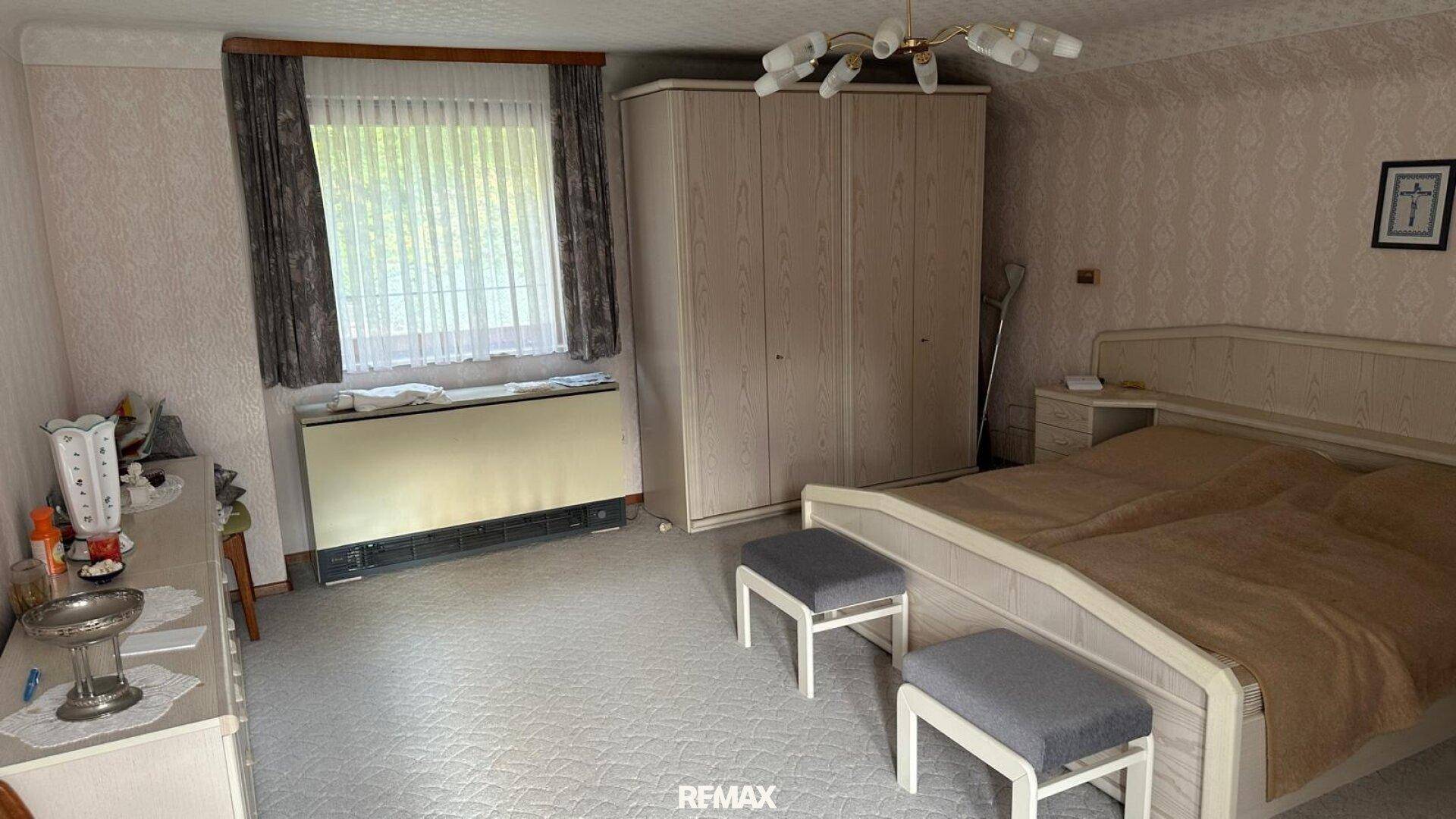 Geräumiges Schlafzimmer mit Doppelbett, Teppichboden, großem Kleiderschrank und Fenster.