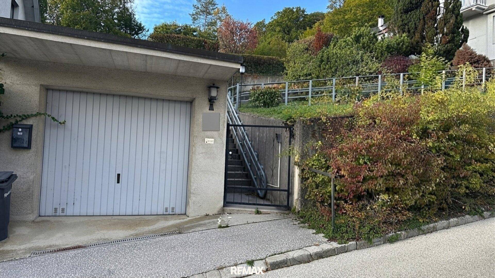 Garagenzufahrt mit Rolltor und Treppe zum oberen Bereich des Grundstücks.