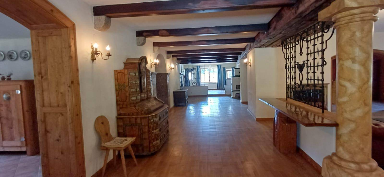 Langer Flur mit Holzbalkendecke, Holzboden und traditionellen Möbeln, der zu weiteren Räumen führt.