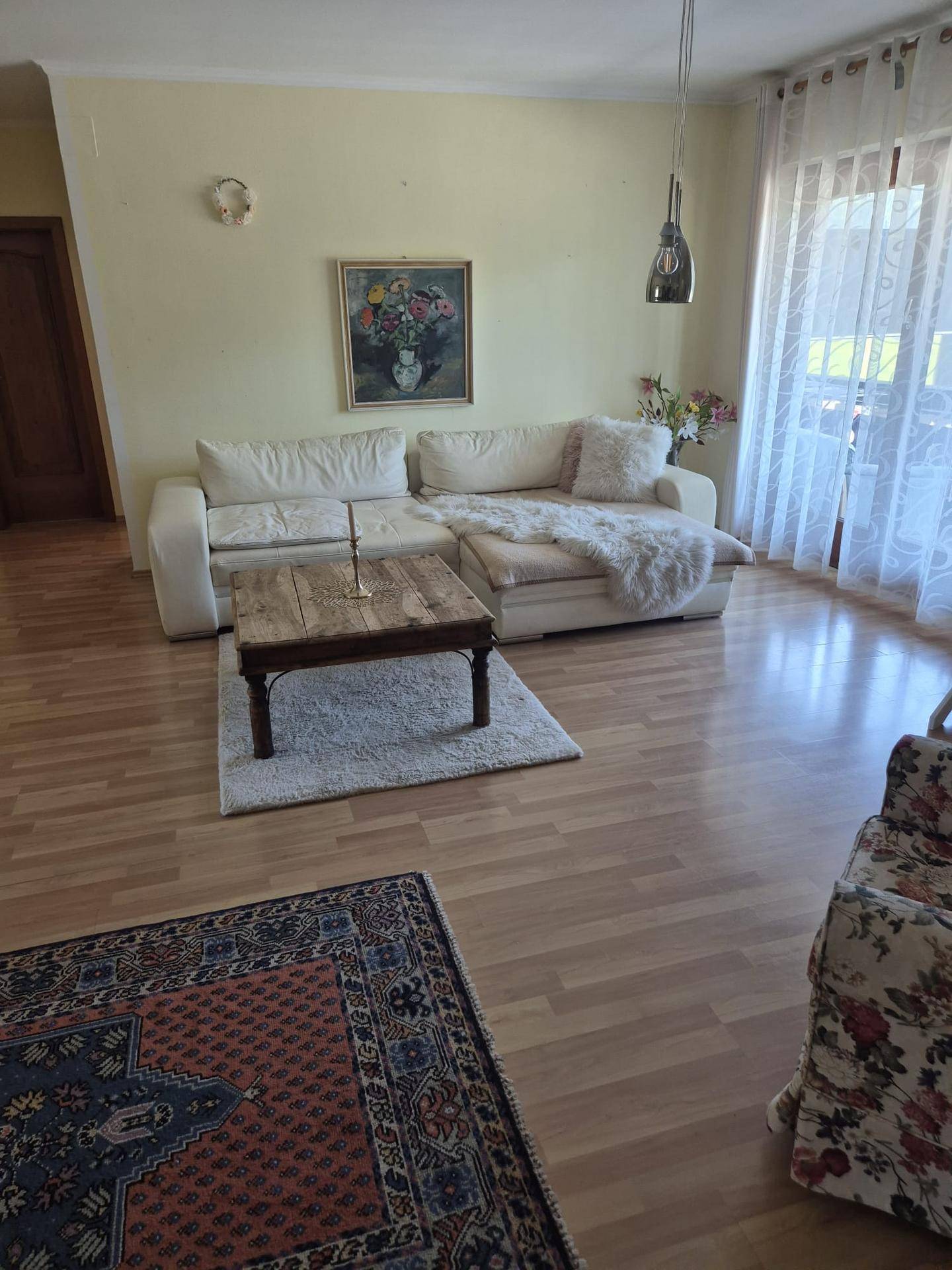 Gemütliches Wohnzimmer mit großem Ecksofa, Holztisch und Teppich auf dem Holzfußboden.
