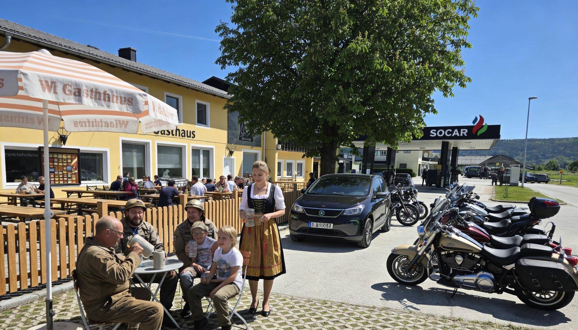 Außenbereich eines Gasthauses mit Gästen auf der Terrasse, umgeben von Motorrädern und einem Auto.