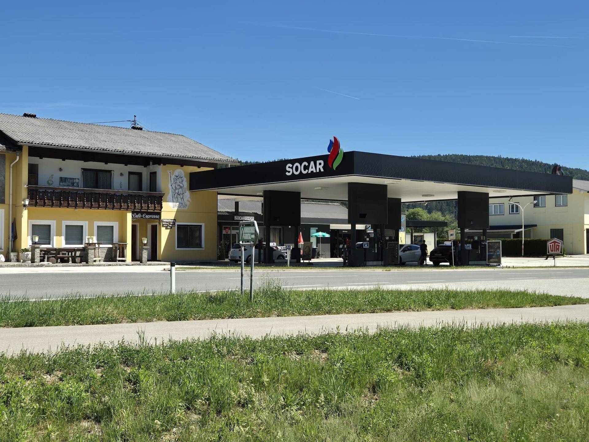 Eine SOCAR Tankstelle mit einem angrenzenden gelben Gebäude unter blauem Himmel.