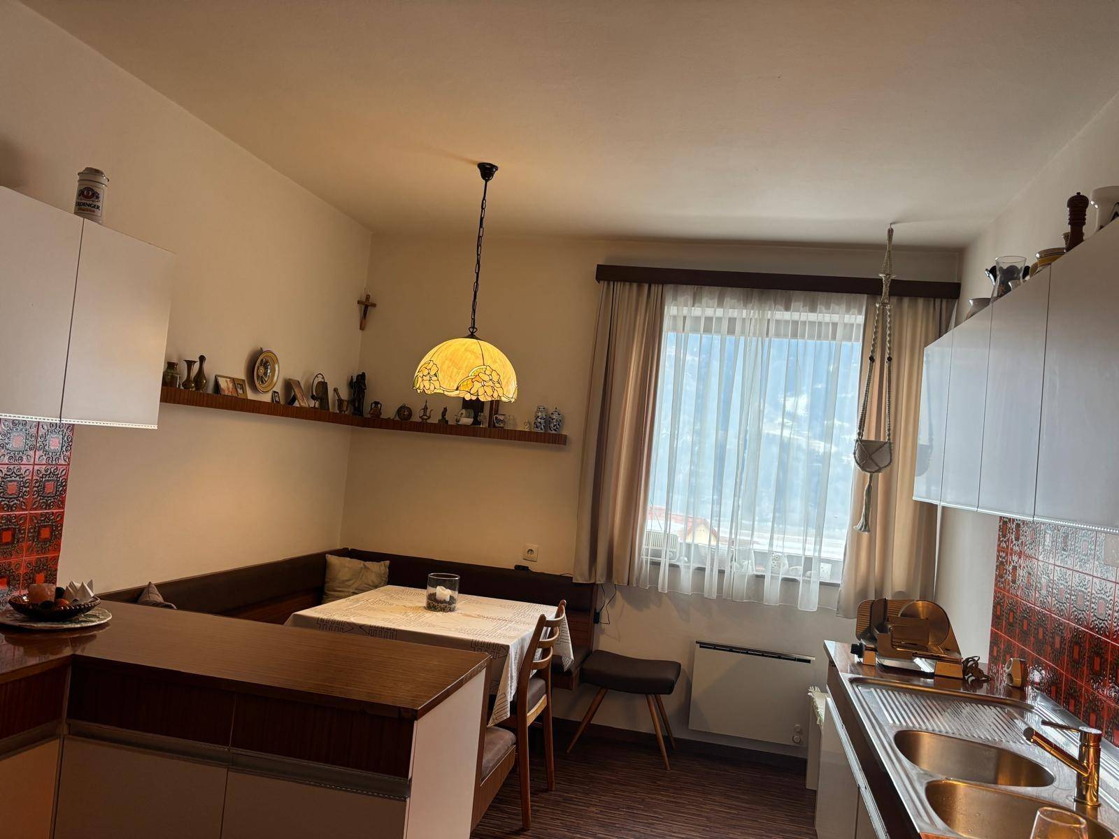 Gemütliche Küche mit Essecke, traditionellen Fliesen und Fenster mit Blick nach draußen.