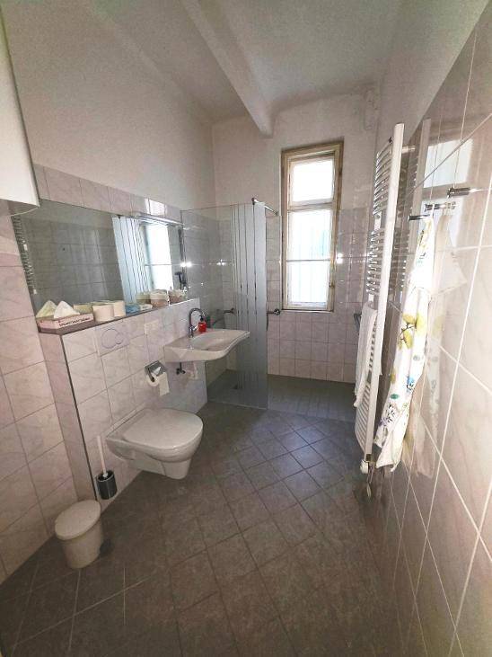 Helles Badezimmer mit Duschkabine, wandhängendem WC und beheiztem Handtuchhalter.