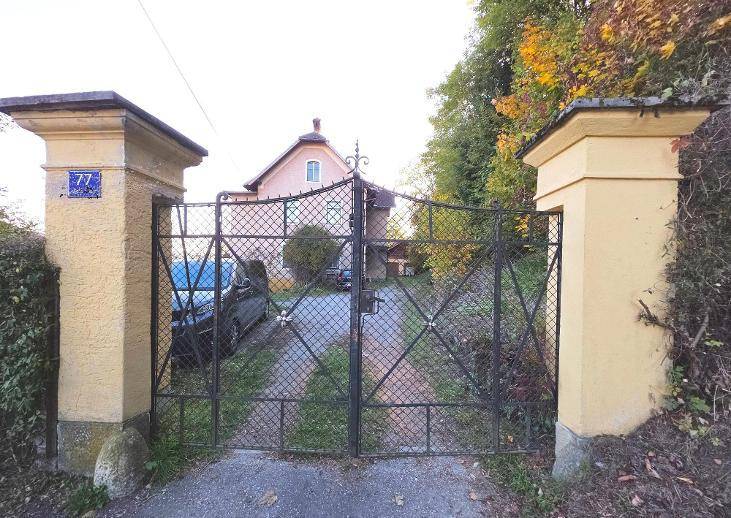 Geschmiedetes Eingangstor mit steinernen Pfeilern führt zum historischen Anwesen.
