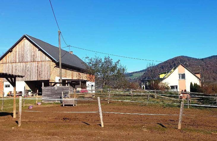 Ländliches Anwesen mit Reitplatz und traditionellen Gebäuden vor einer malerischen Bergkulisse.