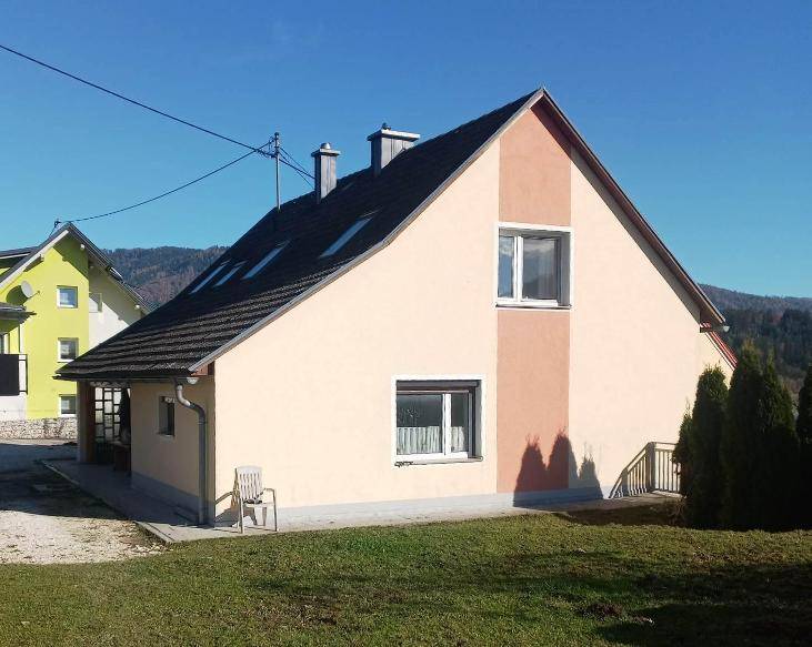 Einfamilienhaus mit hellbeiger Fassade, Satteldach und kleinen Fenstern in ländlicher Umgebung.