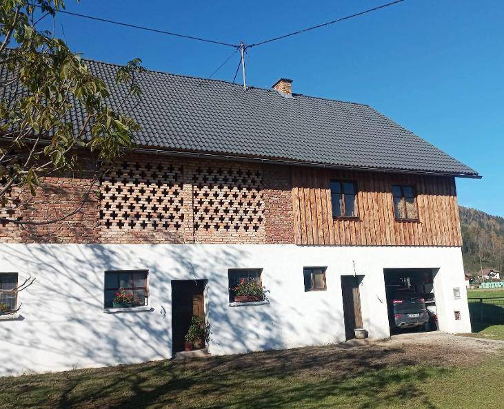 Ländliches Gebäude mit weißer Fassade, Holzelementen und Ziegelmuster, inklusive Garagenzugang.