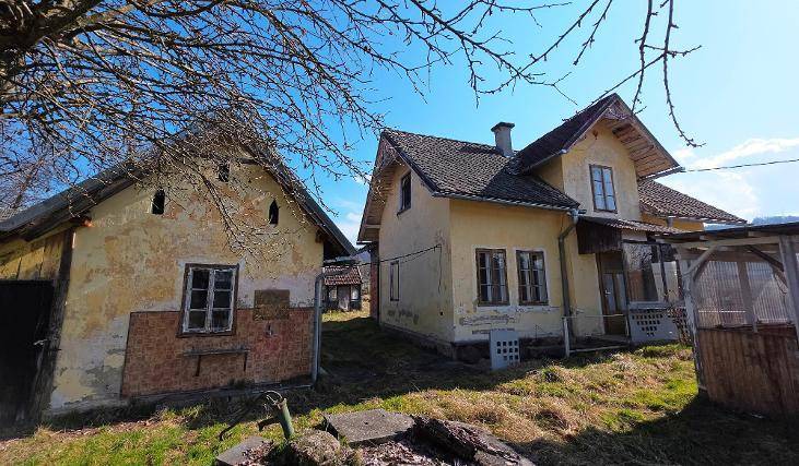 Zwei alte, verwitterte Gebäude mit gelber Fassade und traditionellen Dächern in ländlicher Umgebung.