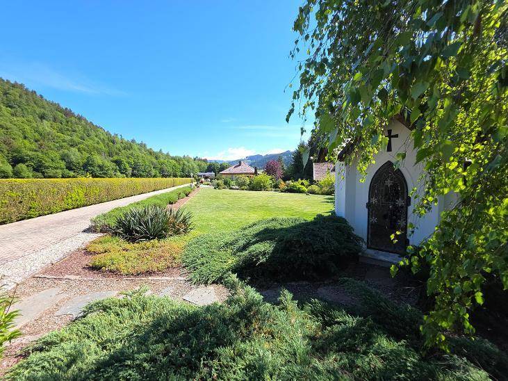 Gepflegter Gartenbereich mit kleiner Kapelle und weitem Blick auf die umliegende Landschaft.