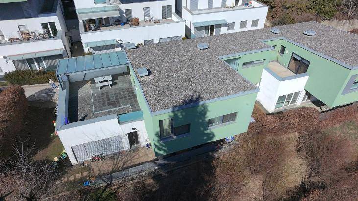 Weitläufige Luftaufnahme eines modernen Wohnhauses mit großer Terrasse in einer Siedlung.