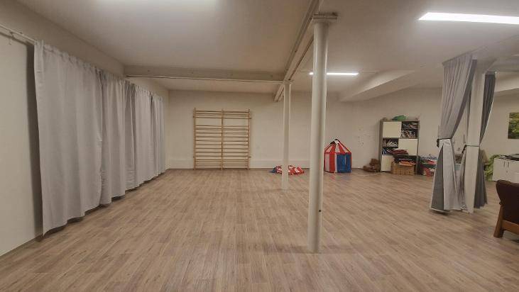 Geräumiger Raum mit Holzboden, Sprossenwand und Vorhängen an der Wand.