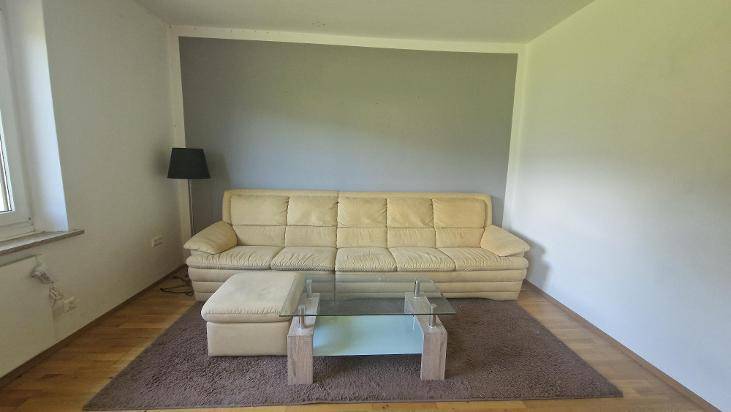 Gemütlicher Wohnbereich mit beigem Sofa, Couchtisch und einer grauen Akzentwand.