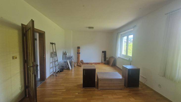 Geräumiges, helles Zimmer mit Holzboden und großen Fenstern, bereit zur individuellen Gestaltung.