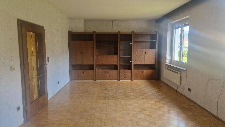 Geräumiges Zimmer mit Parkettboden und einer großen, traditionellen Holzschrankwand.