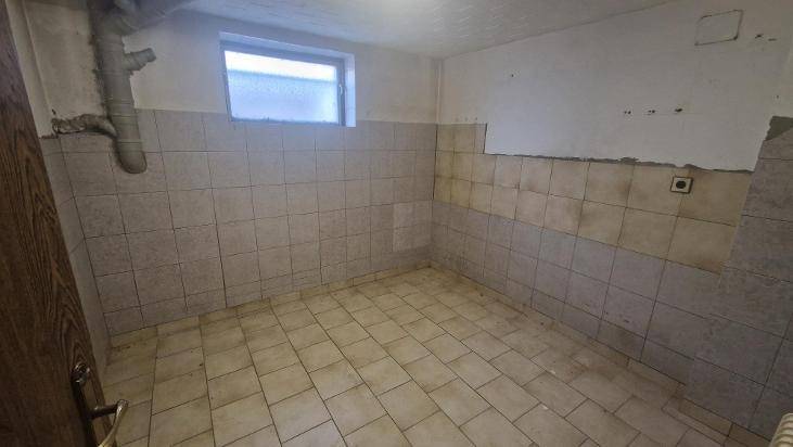 Einfacher Lagerraum im Keller mit Fliesenboden und einem kleinen Fenster.