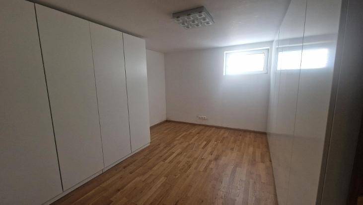Helles Schlafzimmer mit Holzboden und großen weißen Einbauschränken entlang der Wand.