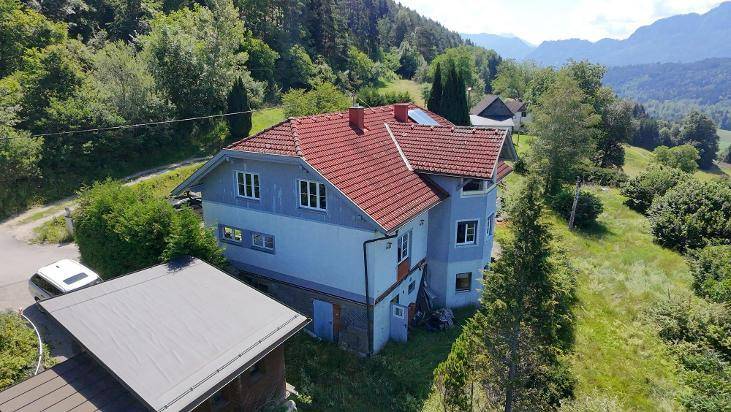 Seitenansicht des Hauses mit rotem Ziegeldach, umgeben von Bäumen und einem Carport.