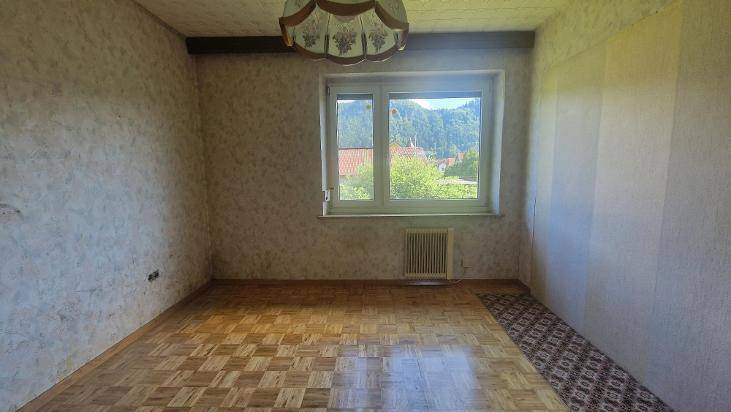 Helles Zimmer mit Parkettboden und Fenster, das einen schönen Bergblick bietet.