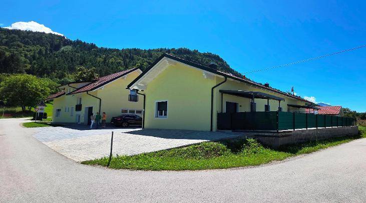 Mehrere gelbe Gebäude mit roten Dächern und einer Terrasse, umgeben von grüner Landschaft.