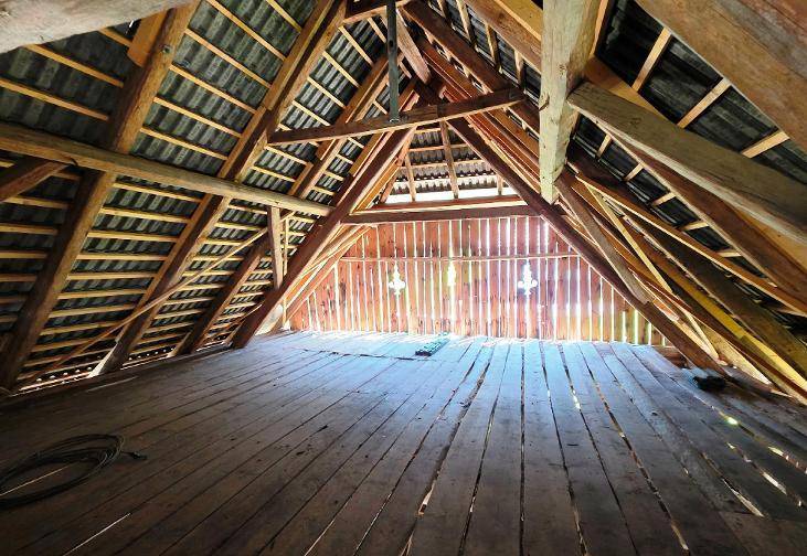 Geräumiger Dachboden mit sichtbaren Holzbalken und Holzdielenboden, bereit für den Ausbau.