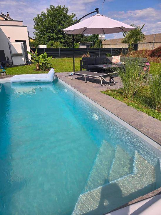 Nahaufnahme des Pools im Garten mit integrierten Stufen und einer aufblasbaren Liege.