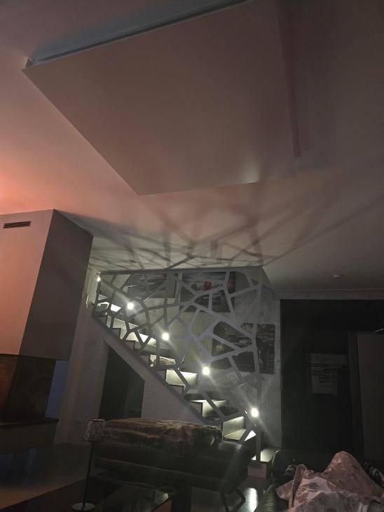 Beleuchtete Treppe mit modernem Design, die in einen Wohnbereich mit indirekter Beleuchtung führt.