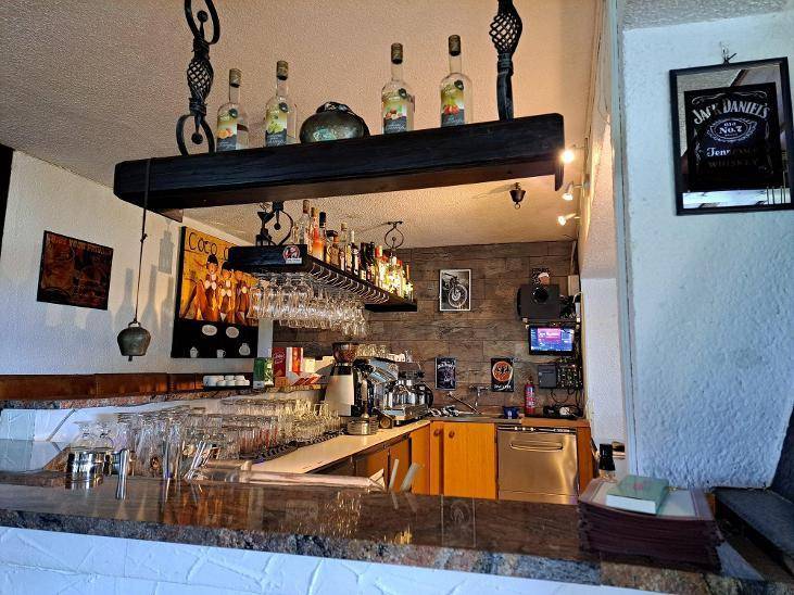 Gut ausgestatteter Barbereich mit Theke, Flaschenregalen, Gläsern und einer Kaffeemaschine, ideal für gesellige Abende.