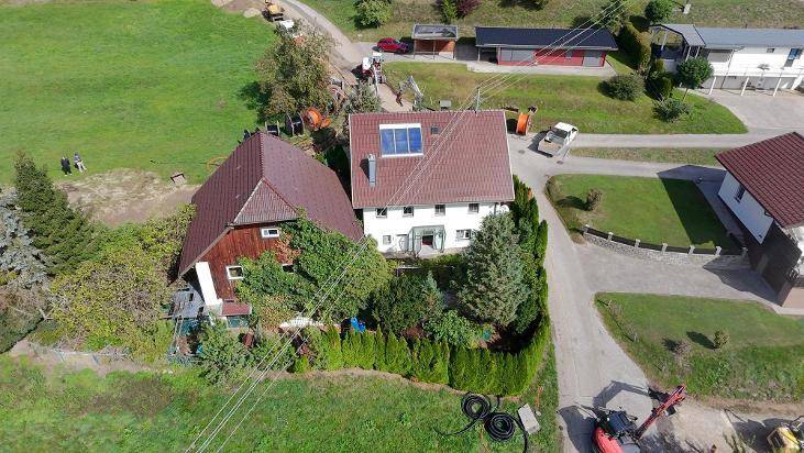 Luftaufnahme eines Wohnhauses mit Garten und angrenzendem Nebengebäude in ländlicher Umgebung.