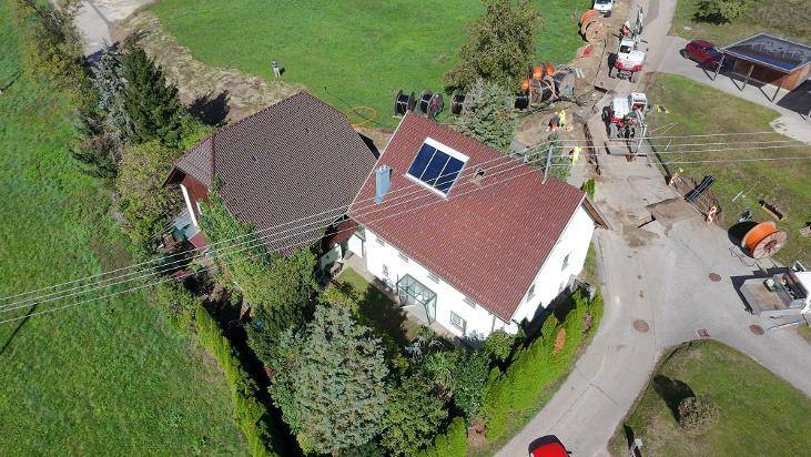 Vogelperspektive des Anwesens mit zwei Gebäuden, umgeben von grünen Feldern und Baustellenaktivitäten.