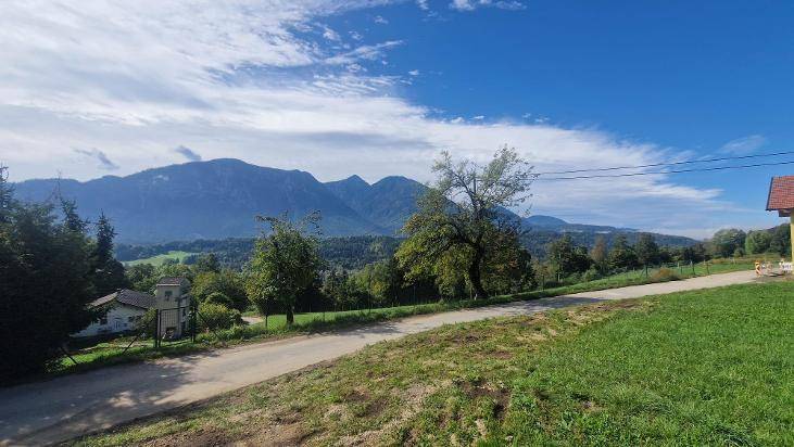 Malerische Landschaft mit weiten grünen Feldern und majestätischen Bergen im Hintergrund unter blauem Himmel.