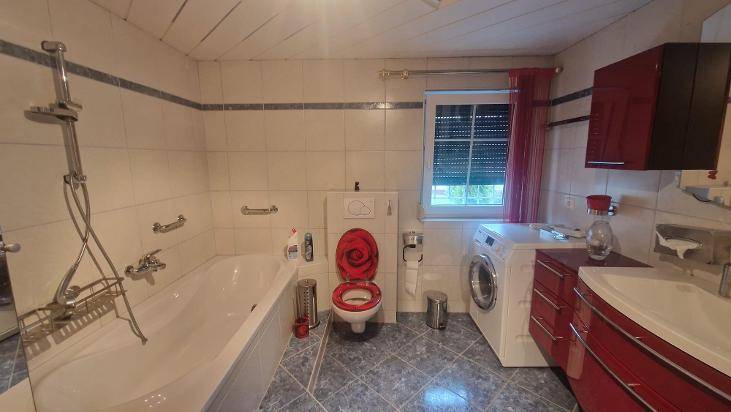 Badezimmer mit Badewanne, WC, Waschmaschine und Fenster, in traditionellem Stil.