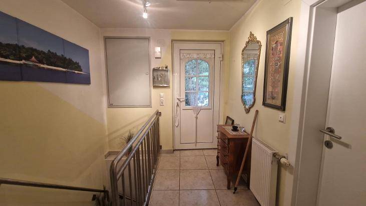 Heller Eingangsbereich mit Fliesenboden, Treppe und einem dekorativen Spiegel.