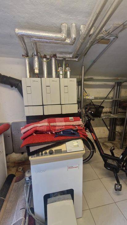 Hauswirtschaftsraum mit Heizungsanlage, sichtbaren Rohren und Fliesenboden.