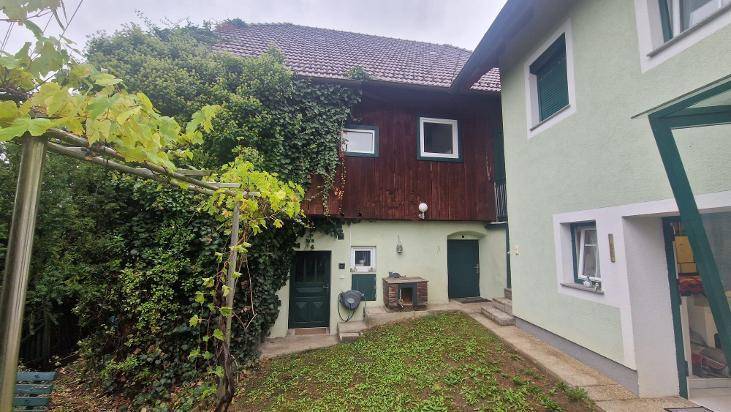 Seitenansicht des Hauses mit Holzbalkon und üppigem Efeu, das die Fassade bedeckt.