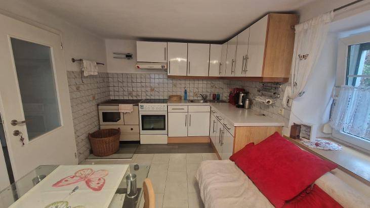 Kleine Küche mit weißen Schränken, Essbereich und Fenster, funktional eingerichtet.