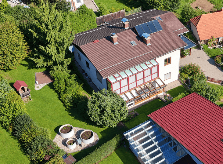 Vogelperspektive des Hauses mit großem, gepflegten Garten, Hochbeeten und einem kleinen Spielhaus.