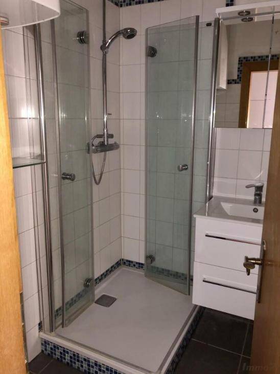 Modernes Badezimmer mit Duschkabine, Waschbecken und weißen Fliesen.