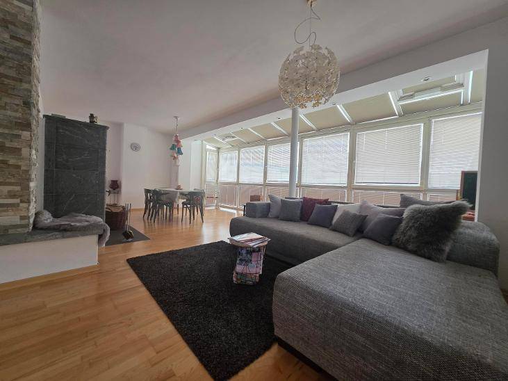 Geräumiger Wohn-Essbereich mit großem Sofa, Holzboden und angrenzendem Wintergarten.