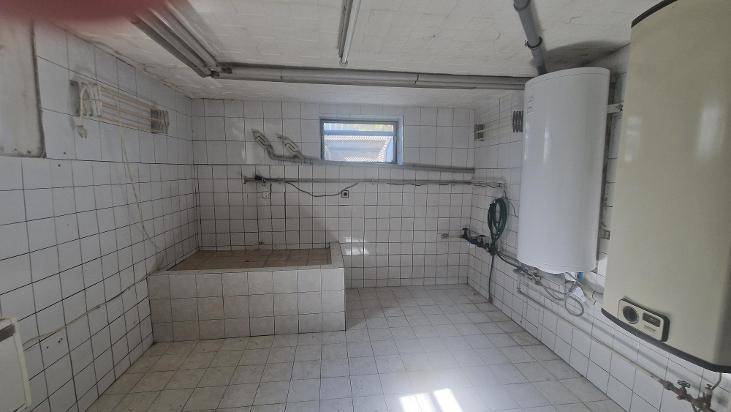 Gefliester Hauswirtschaftsraum im Keller mit Boiler und Waschmaschinenanschluss.