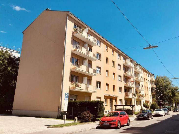 Mehrfamilienhaus mit mehreren Balkonen und gepflegter Fassade an einem sonnigen Tag.