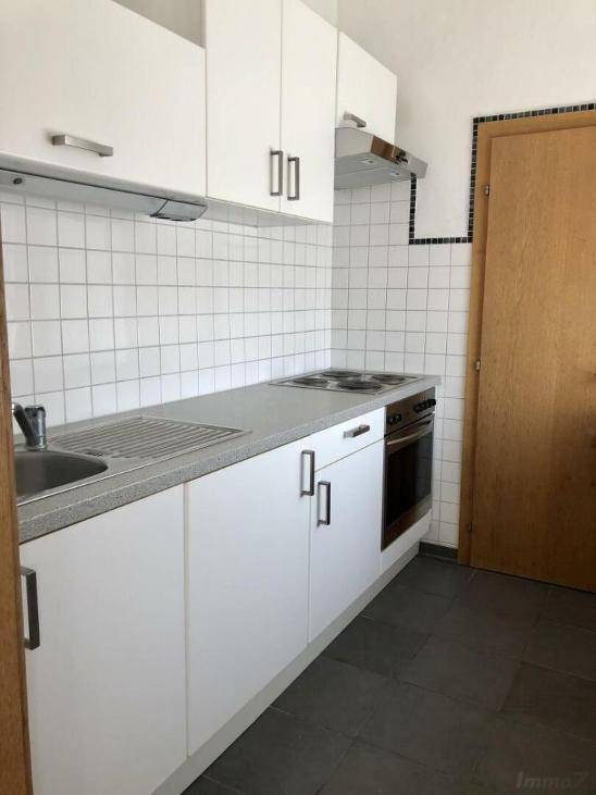 Funktionale Kochnische mit weißen Schränken, Elektroherd und Spüle, ideal für kleine Wohnungen.